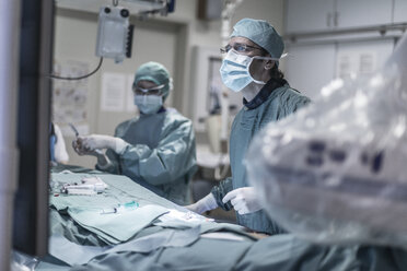 Neuroradiologe in Kittel während einer Operation mit Blick auf den Monitor - MWEF00171