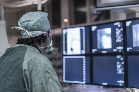 Neuroradiologist in scrubs looking at monitor stock photo