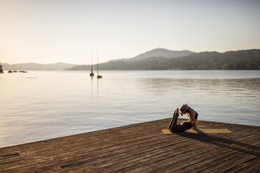 Frau übt Yoga auf einem Steg an einem See - DAWF00567