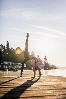 Frau übt Yoga auf einem Steg an einem See - DAWF00570