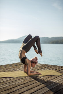Frau übt Yoga auf einem Steg an einem See - DAWF00578