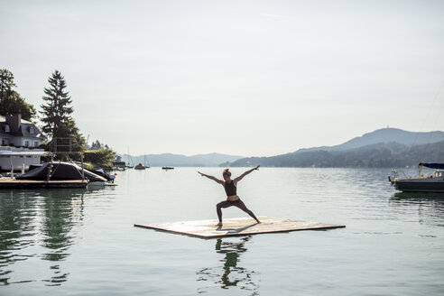Frau übt Yoga auf einem Floß in einem See - DAWF00589