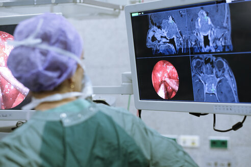 Neurochirurg im Kittel schaut auf den Monitor - MWEF00185