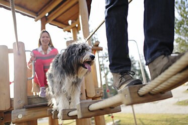 Mann und Frau mit Hund auf Spielplatz - ECPF00176