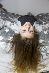 Porträt eines lachenden Mädchens auf dem Bett liegend - SARF03477