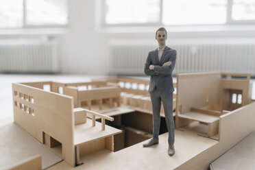 Miniature businessman figurine standing in architectural model - FLAF00118