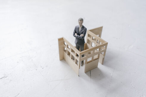 Miniature businessman figurine standing in architectural model - FLAF00119