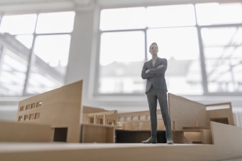 Miniatur-Geschäftsmann-Figur in Architekturmodell stehend, lizenzfreies Stockfoto