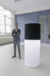 Miniature businessman figurine standing next to smart home device - FLAF00121