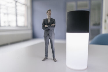 Miniature businessman figurine standing next to smart home device - FLAF00122