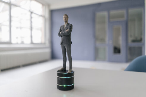 Miniature businessman figurine standing on smart home loudspeaker - FLAF00123