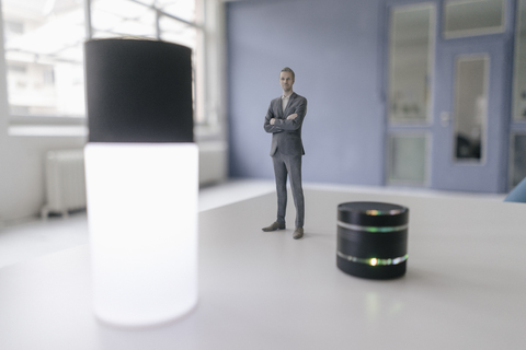 Miniature businessman figurine standing next to smart home devices stock photo