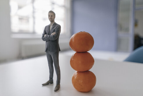 Miniature businessman figurine standing next to clementines - FLAF00129
