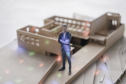 Miniature businessman figurine standing in architectural model with points of light - FLAF00135