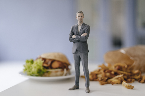 Miniature businessman figurine standing next to fast food stock photo