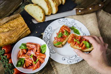 Taking bruschetta, white bread with tomato and olive oil - GIOF03765