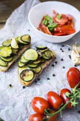 Bruschetta und verschiedene Zutaten, Brot mit Zucchini, Tomate mit Basilikum in Schale - GIOF03787