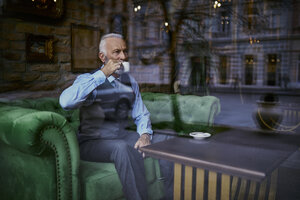 Eleganter älterer Mann sitzt auf der Couch in einem Café und trinkt Kaffee - ZEDF01109