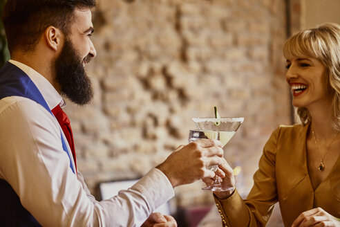 Glückliches elegantes Paar stößt mit Gläsern in einer Bar an - ZEDF01130