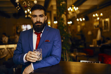 Portrait of elegant young man in a bar holding tumbler - ZEDF01134