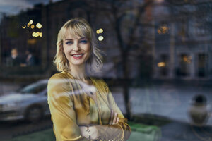 Porträt einer lächelnden eleganten Frau hinter einer Fensterscheibe - ZEDF01141