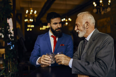 Two elegant men in a bar clinking tumblers - ZEDF01144