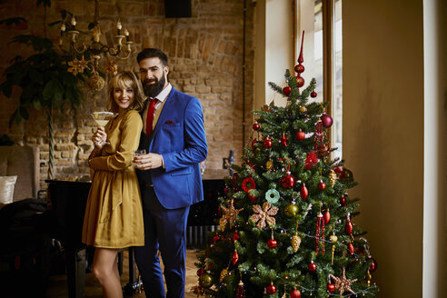 Porträt eines eleganten Paares mit Getränken am Weihnachtsbaum - ZEDF01149