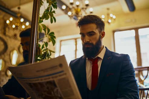Eleganter Mann liest Zeitung in einem Café - ZEDF01175