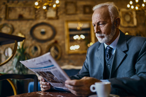 Elegant senior man reading newspaper in a cafe stock photo