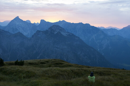 Österreich, Tirol, Wanderer auf einer Almwiese in der Dämmerung - FAF00076