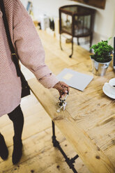 Woman coming home, putting keys on table - GIOF03789