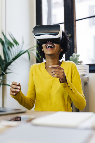 Lachende junge Frau, die ein Spiel spielt und eine Virtual-Reality-Brille trägt, lizenzfreies Stockfoto