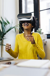 Lachende junge Frau, die ein Spiel spielt und eine Virtual-Reality-Brille trägt - GIOF03812