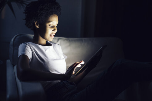 Junge Frau, die nachts online fernsieht und ein digitales Tablet benutzt - GIOF03850