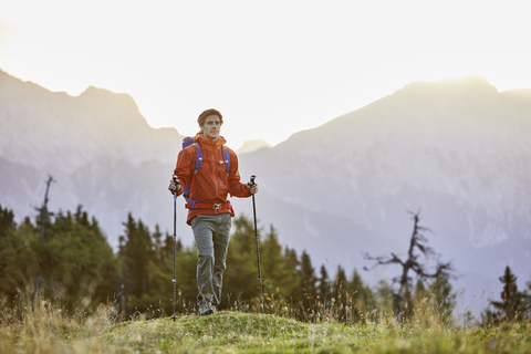 Österreich, Tirol, Mieminger Plateau, Portrait eines Wanderers auf einer Almwiese bei Sonnenaufgang, lizenzfreies Stockfoto