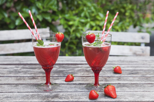 Erdbeerlimonade in Gläsern mit Trinkhalmen auf dem Gartentisch - GWF05389