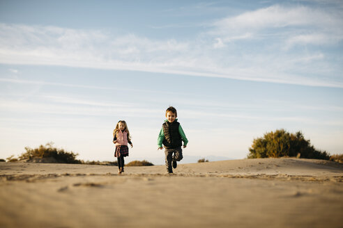 Two children running on the beach in winter - JRFF01529