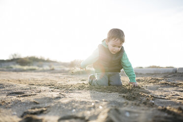 Boy playing with the sand on the beach in winter - JRFF01532