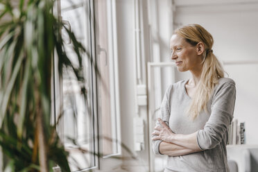 Lächelnde Frau am Fenster stehend - KNSF03552