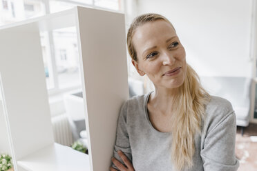 Smiling woman leaning against a shelf - KNSF03555