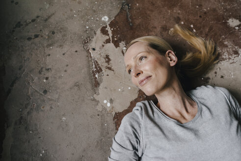 Porträt einer lächelnden Frau, die auf dem Boden liegt - KNSF03557