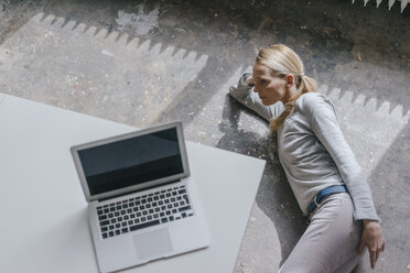 Woman lying on the floor with laptop on table - KNSF03572