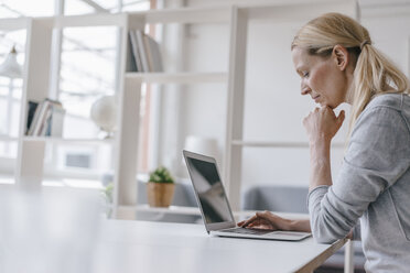 Frau mit Laptop am Schreibtisch im Büro - KNSF03574