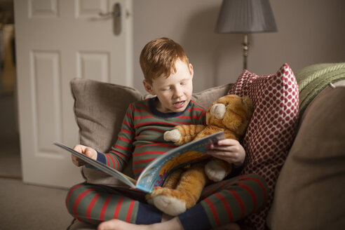 Boy reading a book on couch at home - NMS00196