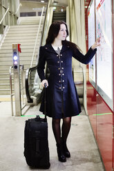 Germany, Cologne, young woman looking at city map in underground station - JATF01001