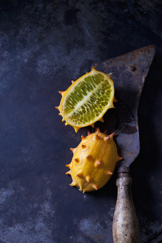 Geschnittener Kiwano und Hackbeil auf rostigem Metall, lizenzfreies Stockfoto