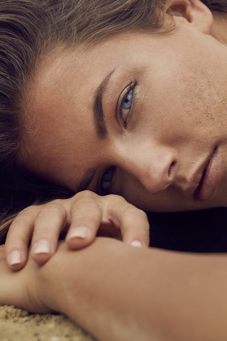 Porträt einer lasziven jungen Frau, die am Strand liegt, Nahaufnahme, lizenzfreies Stockfoto