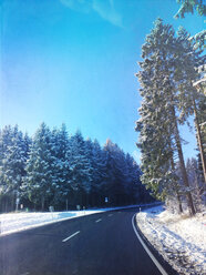 Deutschland, Eifel, Straße im verschneiten Wald - GWF05394