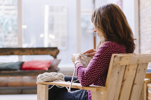 Woman sitting on chair knitting - OCAF00025