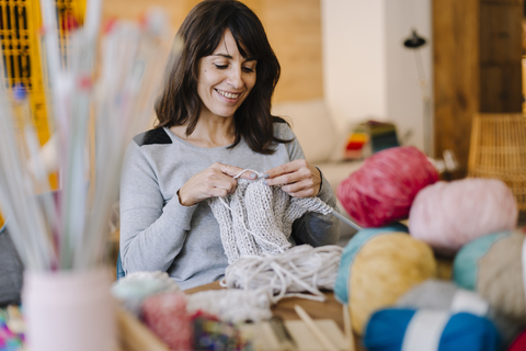 Smiling woman at table knitting stock photo